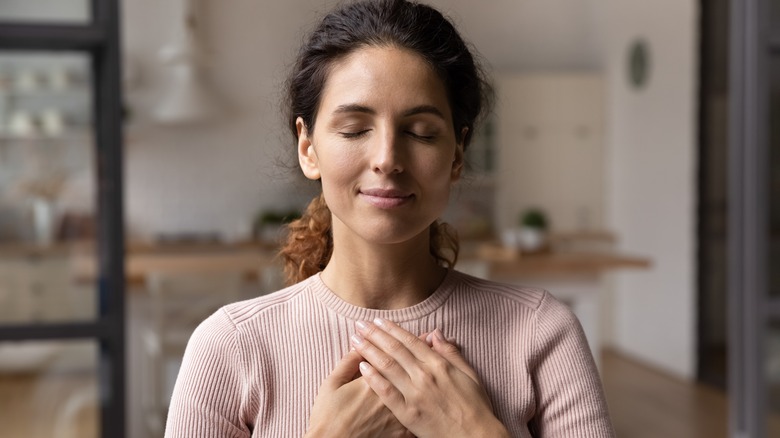 woman holding hands over heart