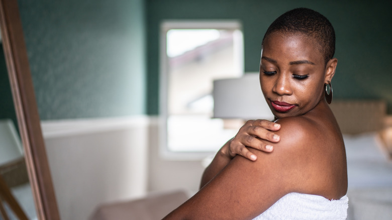 woman applying cream to shoulder