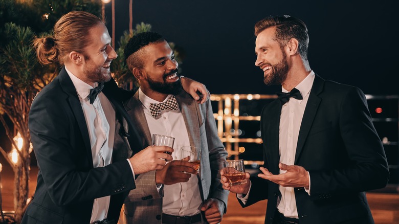 Male wedding guests enjoying drinks at night