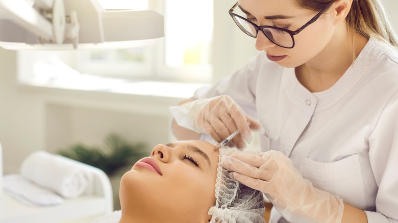 Provider injecting patient's forehead with filler