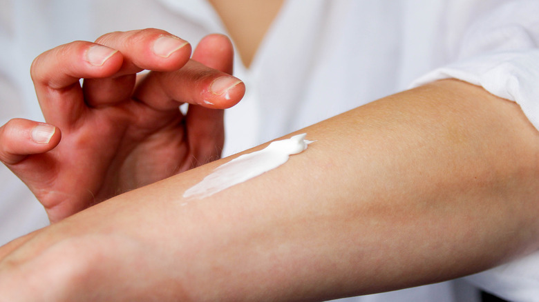 Woman applying lotion to arm