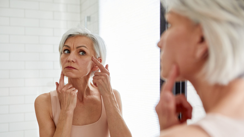 woman looking at face in mirror