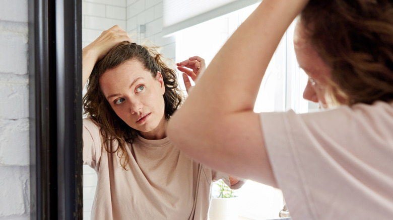 Woman examining hair in mirror