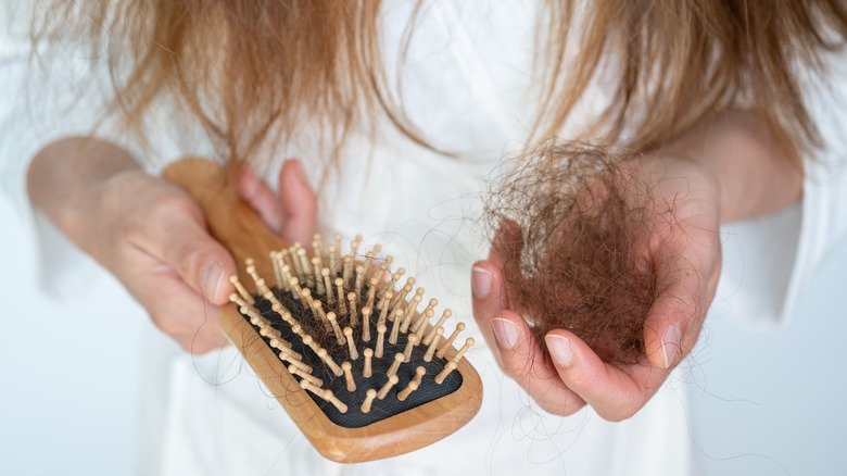 Woman's hands cleaning hair from hairbrush