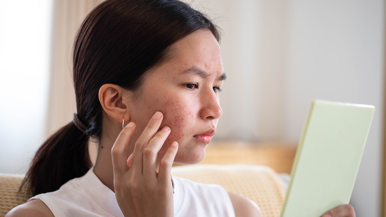 A woman examining her face