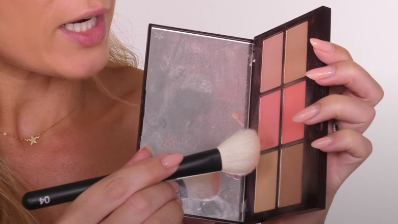 woman putting brush in blush