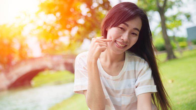 Smiling woman poking cheeks 