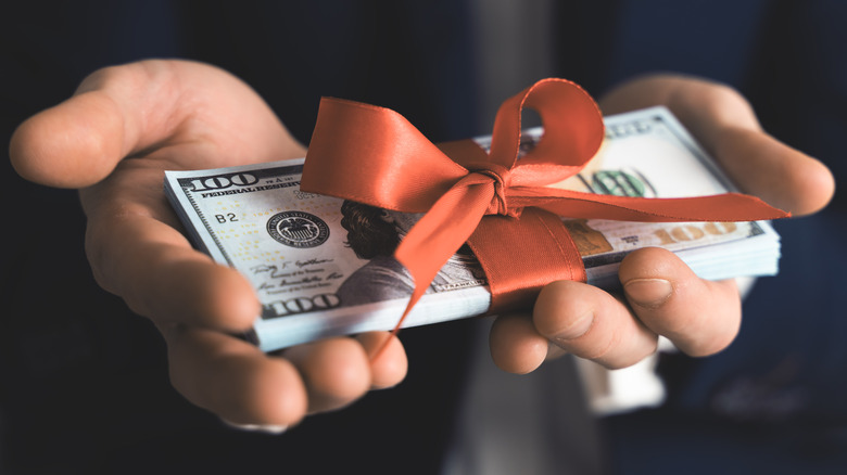 hands holding ribbon-wrapped money