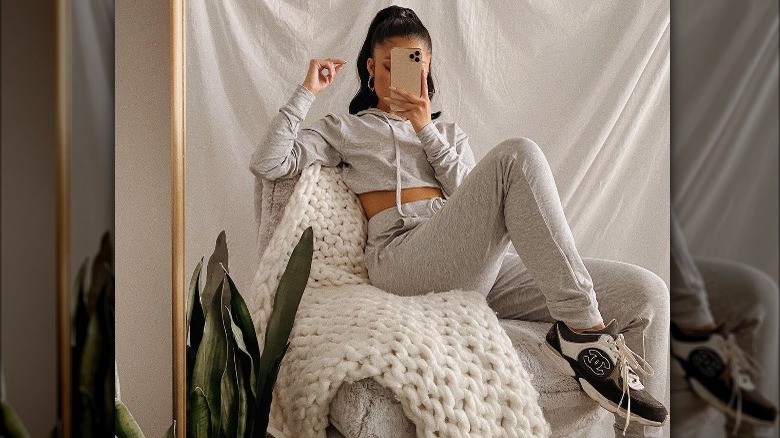 Woman takes selfie in cropped gray sweat suit