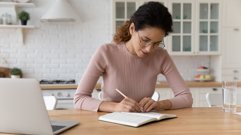 Woman writing at kitchen counter