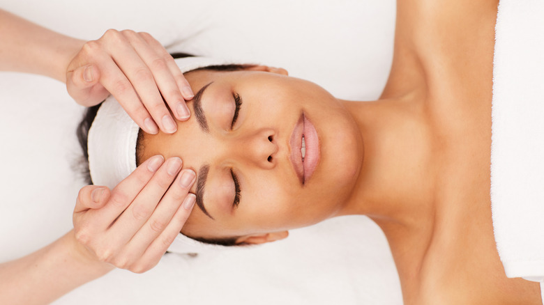 relaxed woman receiving facial massage
