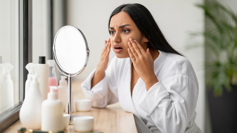 Woman analyzing puffy face in mirror