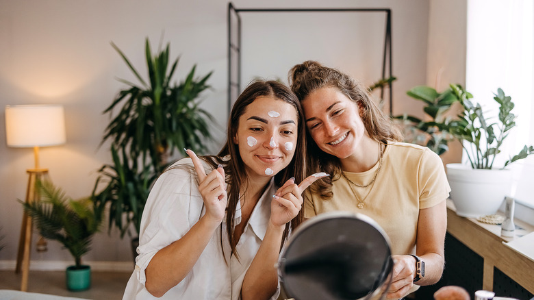 Smiling women applying lotion