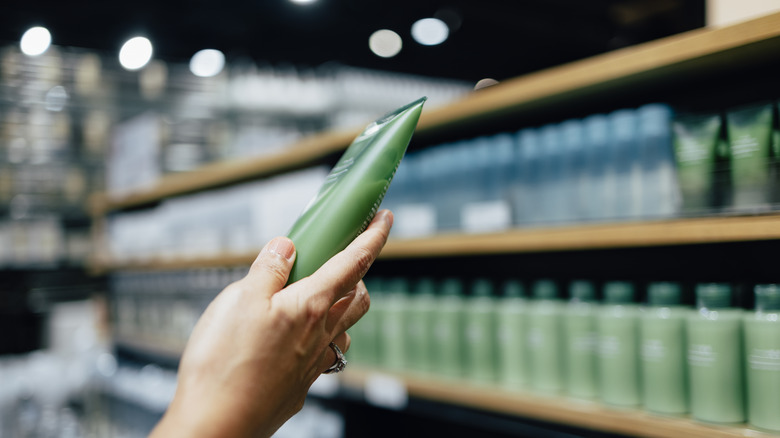 Hand holding skincare product in store