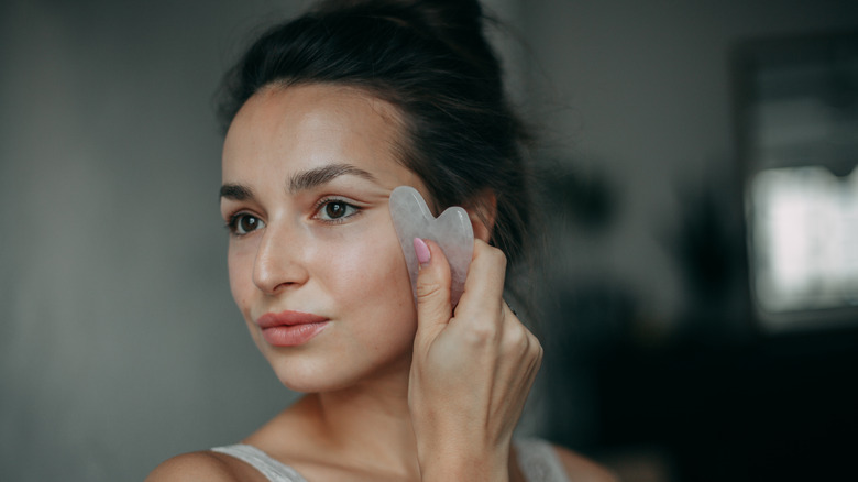 woman using gua sha to massage face