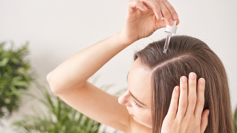 Woman applying oil to hair