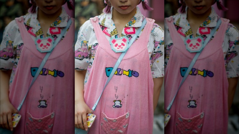 Woman wearing kidcore style outfit with pink overalls