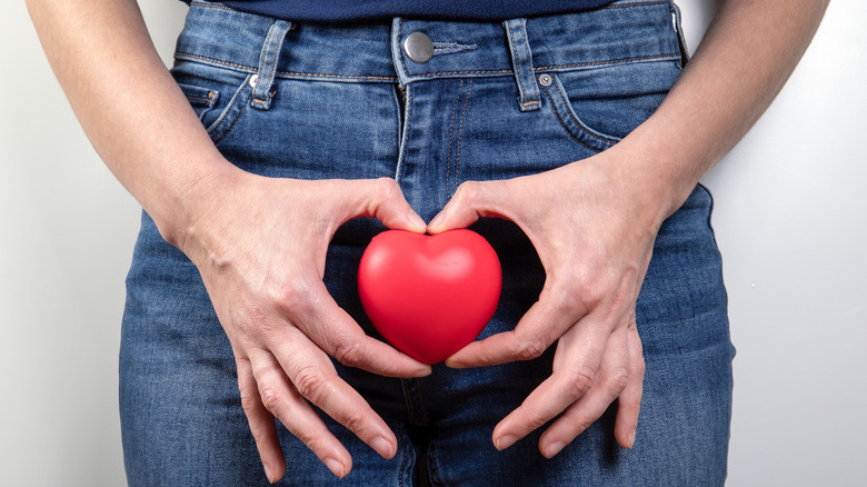 Person holding heart in front of pelvis
