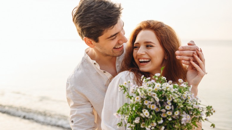 Man surprising woman with flowers