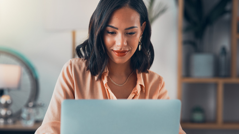 Satisfied woman smiling at laptop