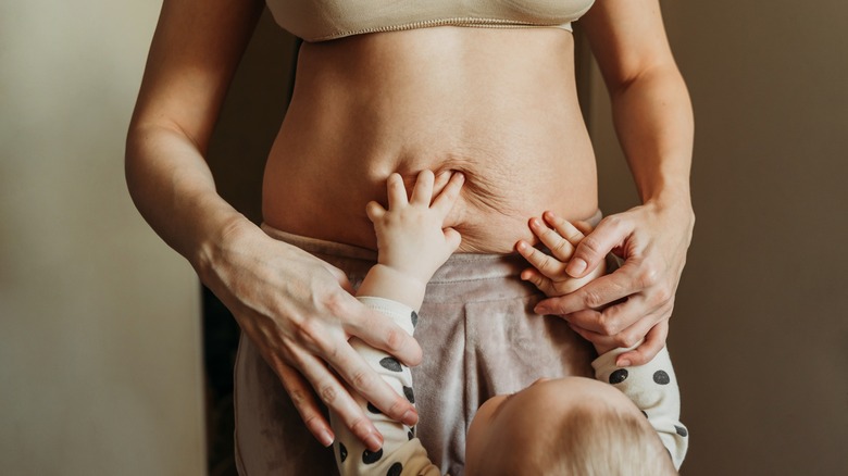 Child touching mother's belly with pregnancy marks