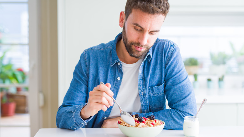 man eating cereal with fruit