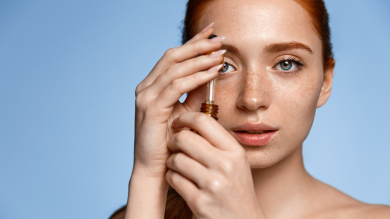 red headed woman with freckles holding oil