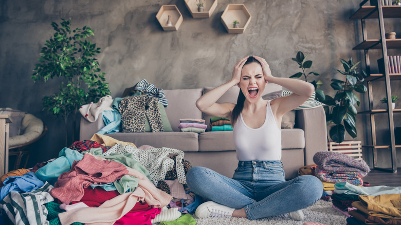 Frustrated woman amidst clothes pile