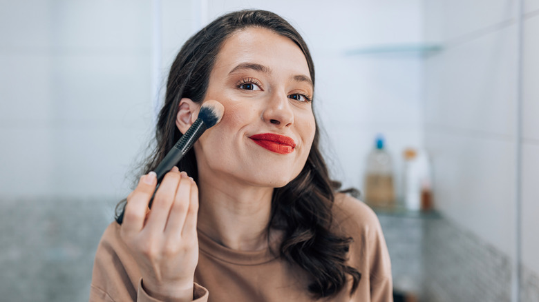 Young woman applying blush