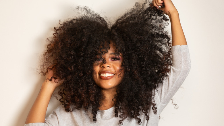 smiling woman touching brown curly afro