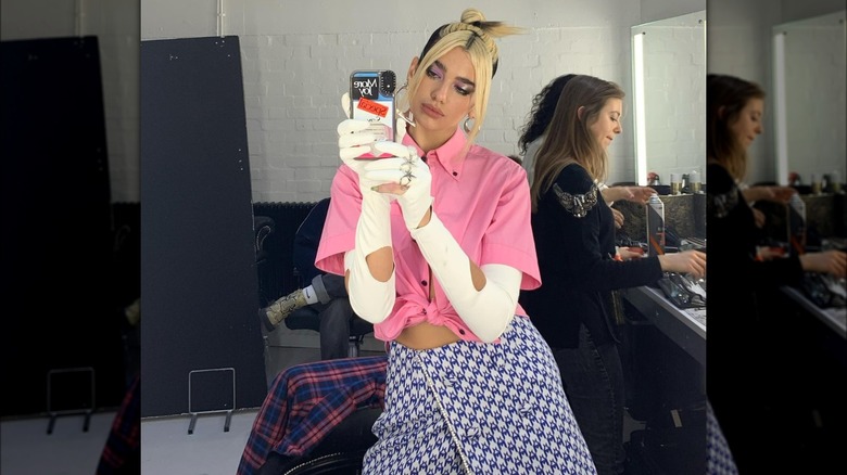 Dua Lipa taking a mirror selfie with a skunk hair updo