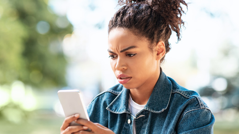 Black woman frowning at smartphone