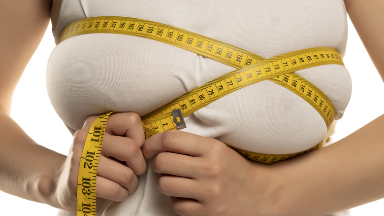 Woman measuring her breasts with yellow tape measure