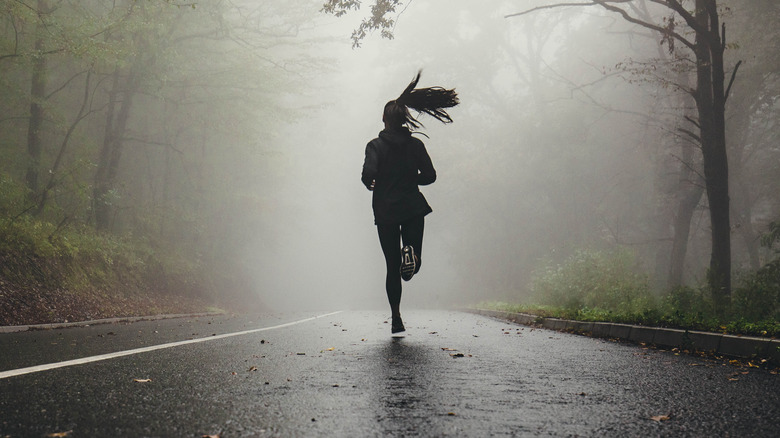 Woman running on misty road