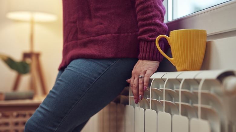 Woman sitting on heater