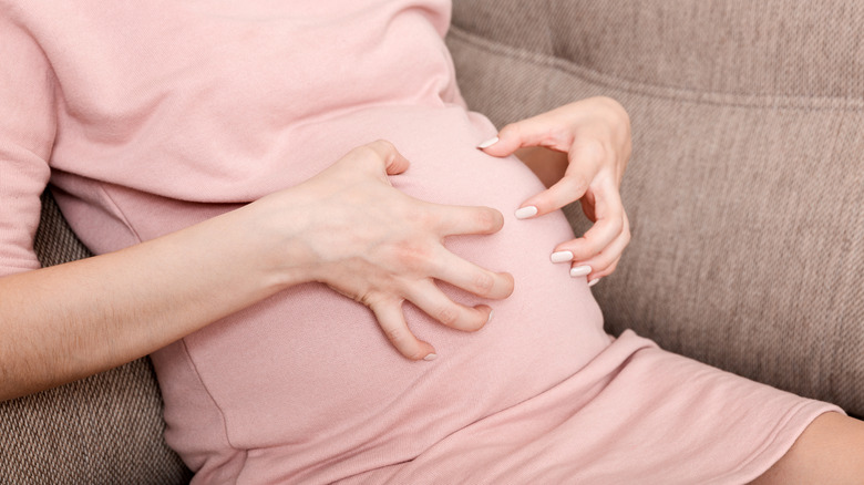 Pregnant woman scratching stomach