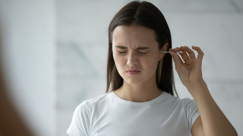 Woman cleaning ear with cotton swab