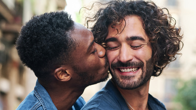 A man kissing his smiling partner on the cheek.