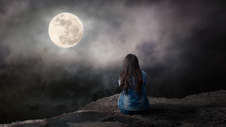 Woman looking at the full moon