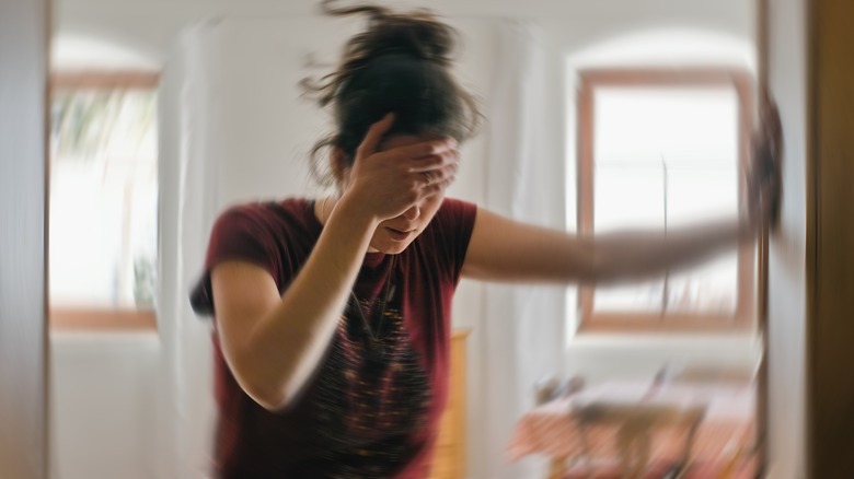 Disoriented woman holds onto wall for support