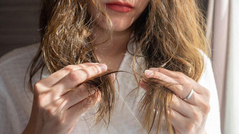 woman looking at her damaged hair