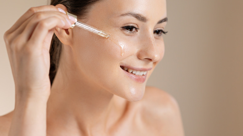 Woman applying oil to face