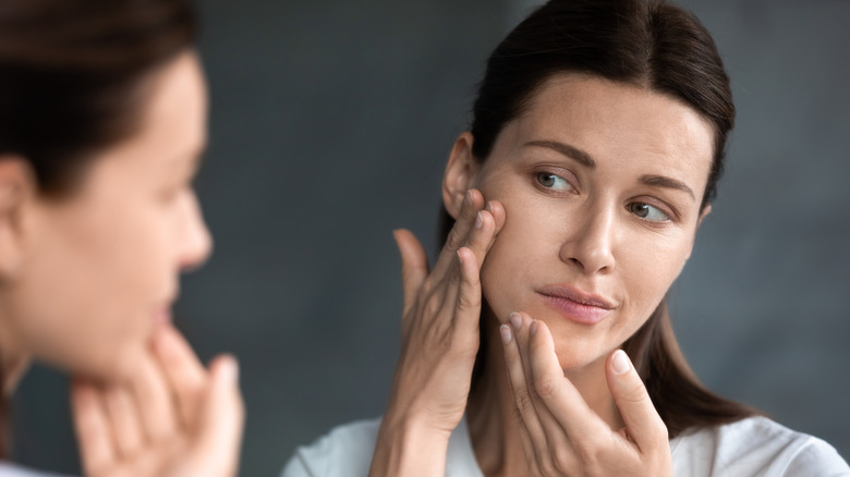 Woman looking at skin in mirror