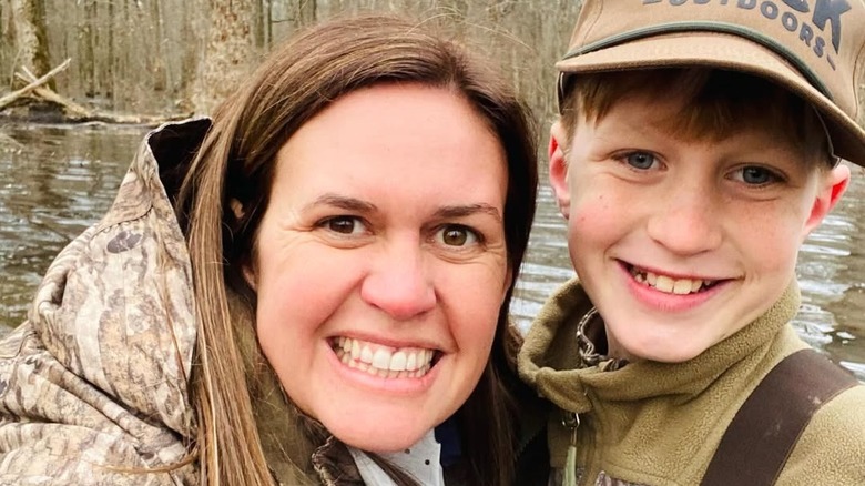 Sarah Huckabee Sanders poses with her son in the woods.