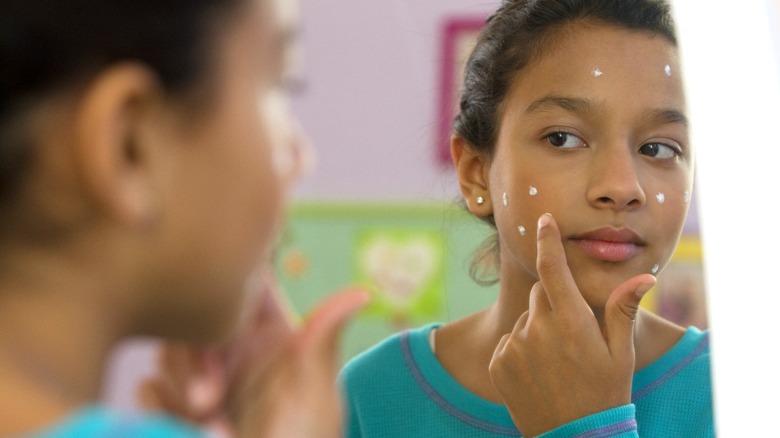 Young girl applying face cream