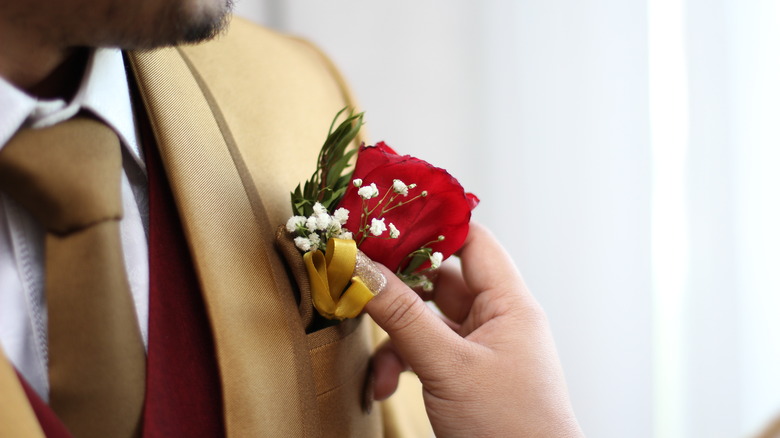 pinning boutonniere onto man's jacket 