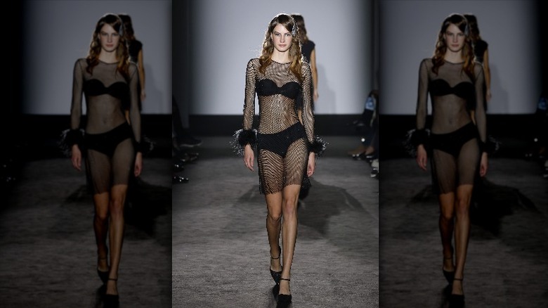 model walking on runway wearing sheer dress