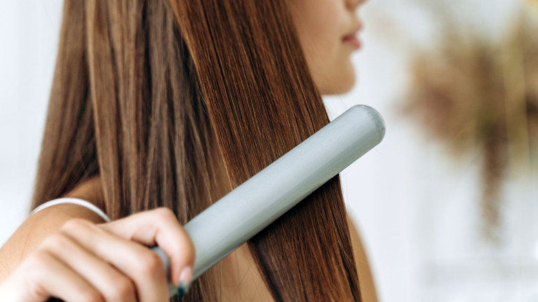 woman using flat iron 