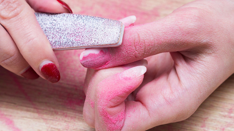 person filing off acrylic nails