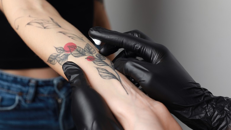 woman applying cream to tattoo